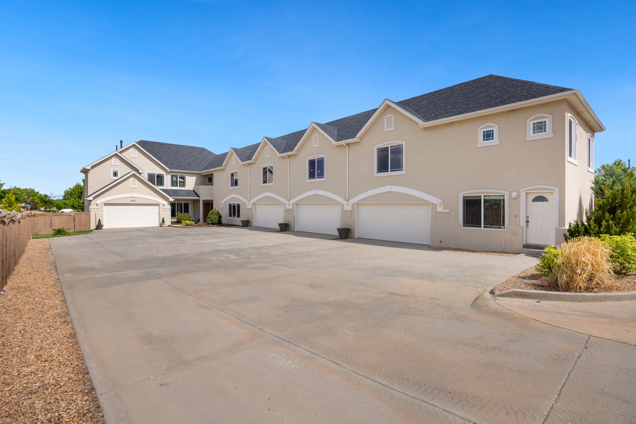 gallery-1 A modern suburban residential building featuring a large driveway under a clear blue sky.