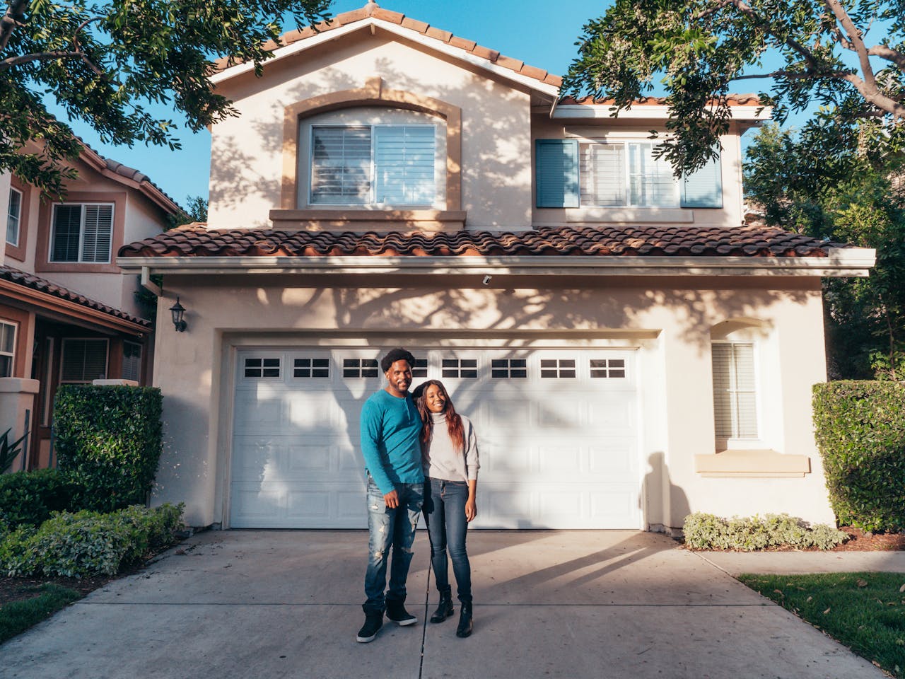 about-01 A joyous couple stands together in front of their newly purchased house, symbolizing new beginnings.
